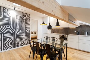 Enjoy meals at the sleek dining table surrounded by black chairs, set against a striking abstract wall.