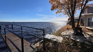 A waterfront property with a metal railing, a staircase leading to a dock, and a house with a large window overlooking the water.