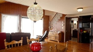 A dining area with a wooden table, chairs, a red pot, and a chandelier.