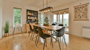 Ett modernt kök med ett träbord, svarta stolar och en hängande lampa.