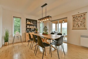 Une cuisine moderne avec une table en bois, des chaises noires et un luminaire suspendu.