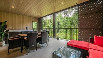 Un intérieur moderne comprenant un coin repas, un canapé rouge et une grande fenêtre donnant sur un jardin.