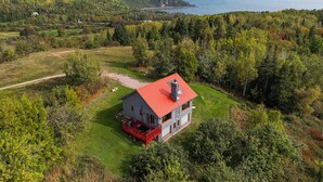 Una casa dal tetto rosso e dalle pareti bianche, immersa in un paesaggio verdeggiante con vista sul mare.