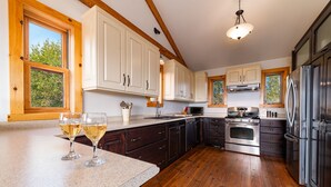 Una cucina con pavimento in legno, mobili bianchi, elettrodomestici in acciaio inossidabile e un'ampia finestra che garantisce luce naturale.