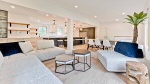 A modern living room with a sectional sofa, a coffee table, and a dining area with chairs. - Hôtel à la maison - Ô coeur d'Eastman avec spa ! (Eastman)
