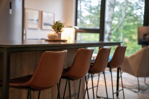 Een bar met een houten toonbank en vier bruine stoelen.