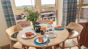 Une table de petit-déjeuner avec des croissants, du café, du jus de fruits et une vue sur la campagne.