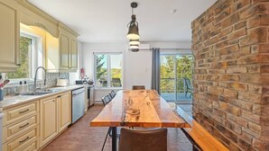 Una cocina moderna con una mesa de madera, armarios de colores claros y una pared de ladrillo.