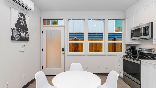 A modern kitchen with white cabinets, a built-in oven, and a microwave. - Skywalker Rebel Base (Seattle)