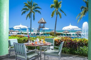 Enjoy a leisurely meal with a view of the pool and beach from this serene outdoor dining area.