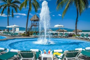Relax by the resort pool surrounded by palm trees and lounge chairs.