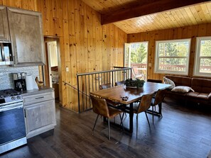 A wooden cabin interior with a kitchen, dining area, and a cozy seating area. - cabin with a view (Big Bear Lake)