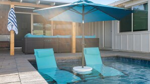 Une piscine avec deux chaises longues et un parasol bleu.