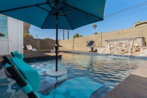 A swimming pool with a blue umbrella, lounge chairs, and a stone wall. - Old Town Scottsdale Desert Oasis- FREE heated pool (Scottsdale)