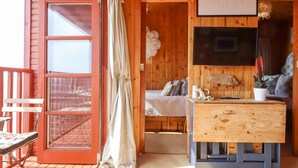 Una habitación acogedora con paredes de madera, una cama con almohadas, un televisor y una pequeña mesa con una planta.