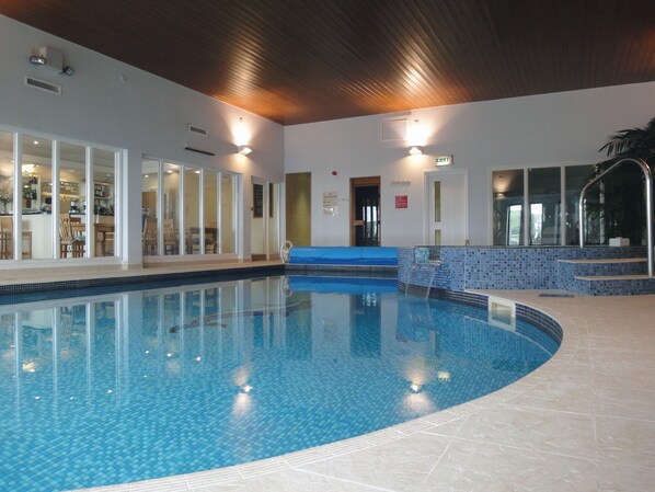 An indoor swimming pool with clear blue water, tiled walls, and a wooden ceiling. - 4 Burgh Island Causeway (Kingsbridge)