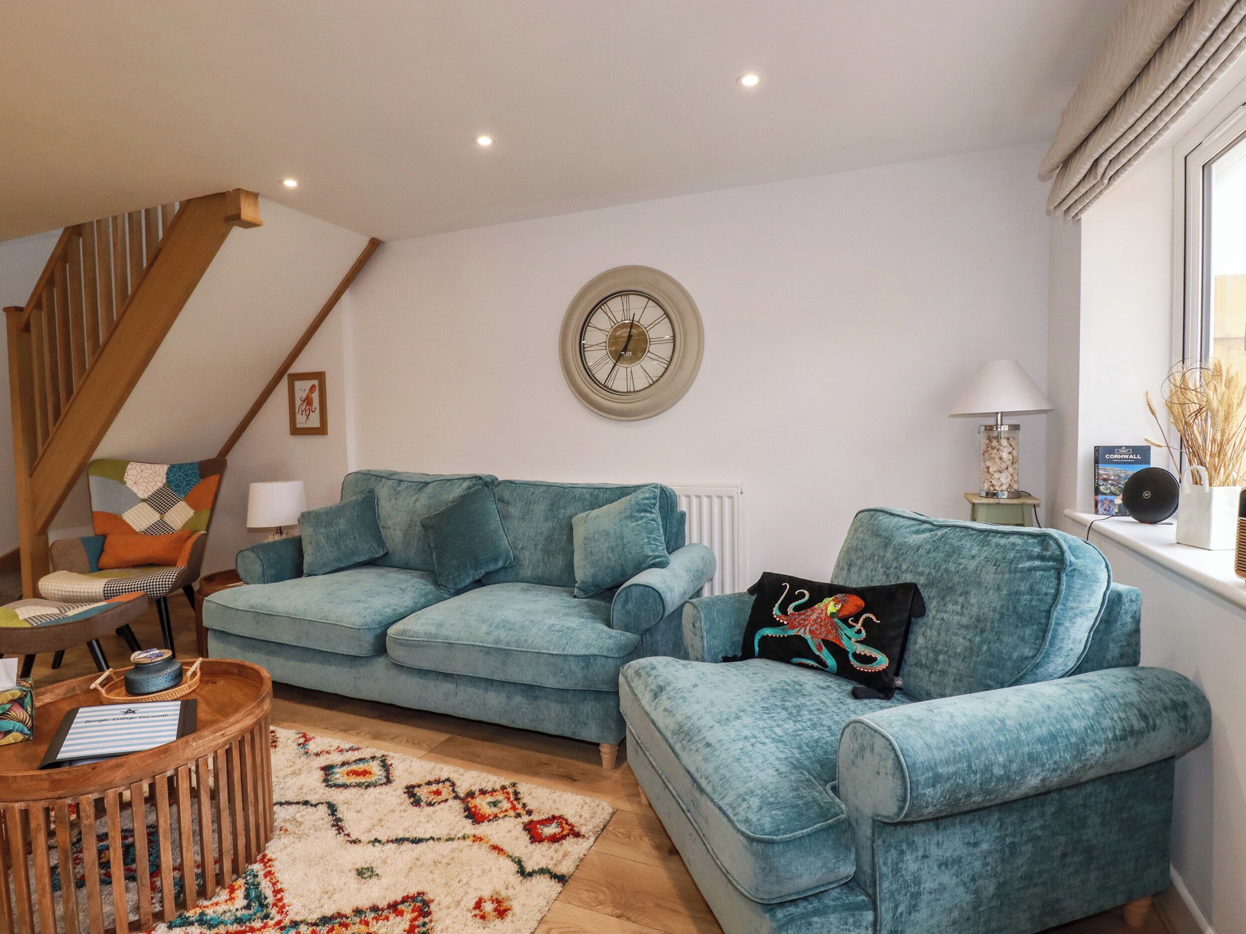 A living room with a blue sofa, a wooden coffee table, and a patterned rug.