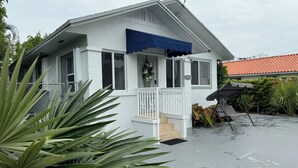 A white house with a porch, a swing chair, and a covered patio area.