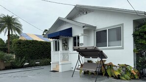 A white house with a covered porch, a swing chair, and a small garden.