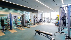 Una palestra moderna con diverse attrezzature per l'allenamento, ampie finestre e un ambiente pulito e spazioso.
