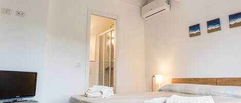 Une chambre d’hôtel avec un lit, une télévision, une douche et des œuvres d’art accrochées au mur.