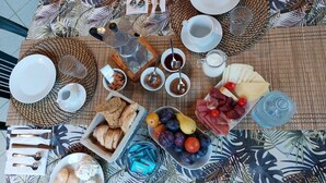 A table set with various breakfast items including bread, fruits, cheese, and condiments. - Alghero in Bicicletta (Alghero)