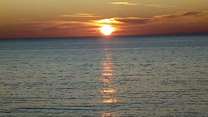 A sunset over a calm sea with the sun reflecting on the water. - Alghero in Bicicletta (Alghero)
