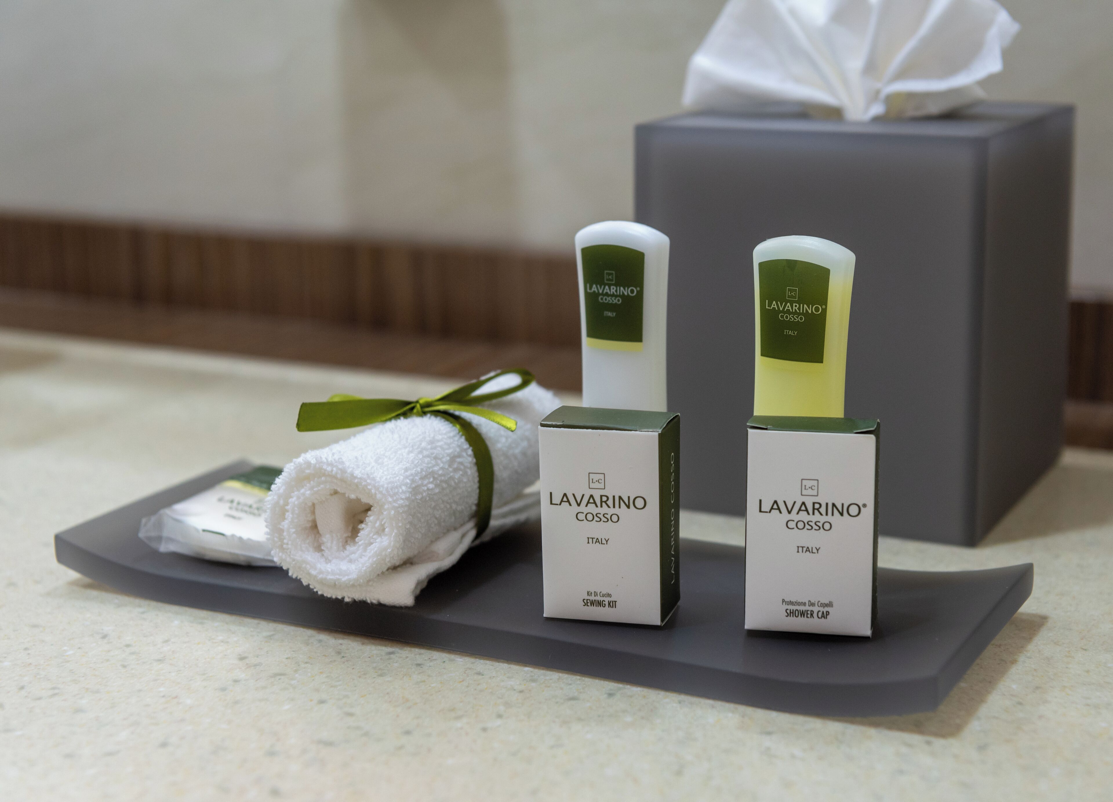 Un conjunto de accesorios de baño ordenado que incluye una toalla, un kit de costura y un gorro de ducha, todo con la marca 'LAVARINO COSSO ITALY'.