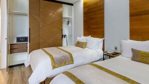 Une chambre d’hôtel avec deux lits, une armoire, un dressing et un mur d’accent en bois.
