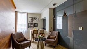 Un salon moderne avec deux fauteuils en cuir, une table ronde et un mur d’accent de couleur foncée.