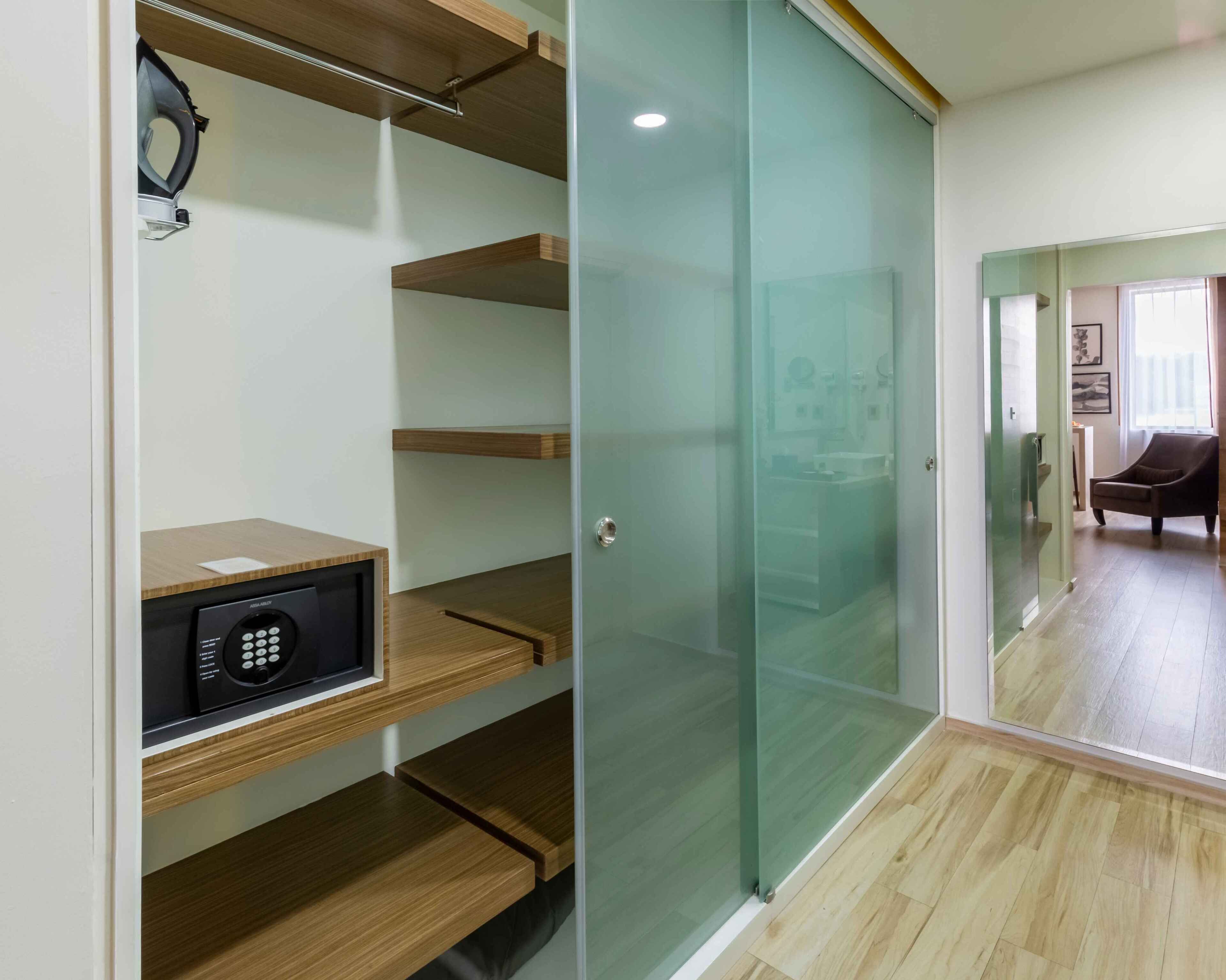 Una habitación moderna con una caja fuerte empotrada, estanterías de madera y un separador de vidrio.