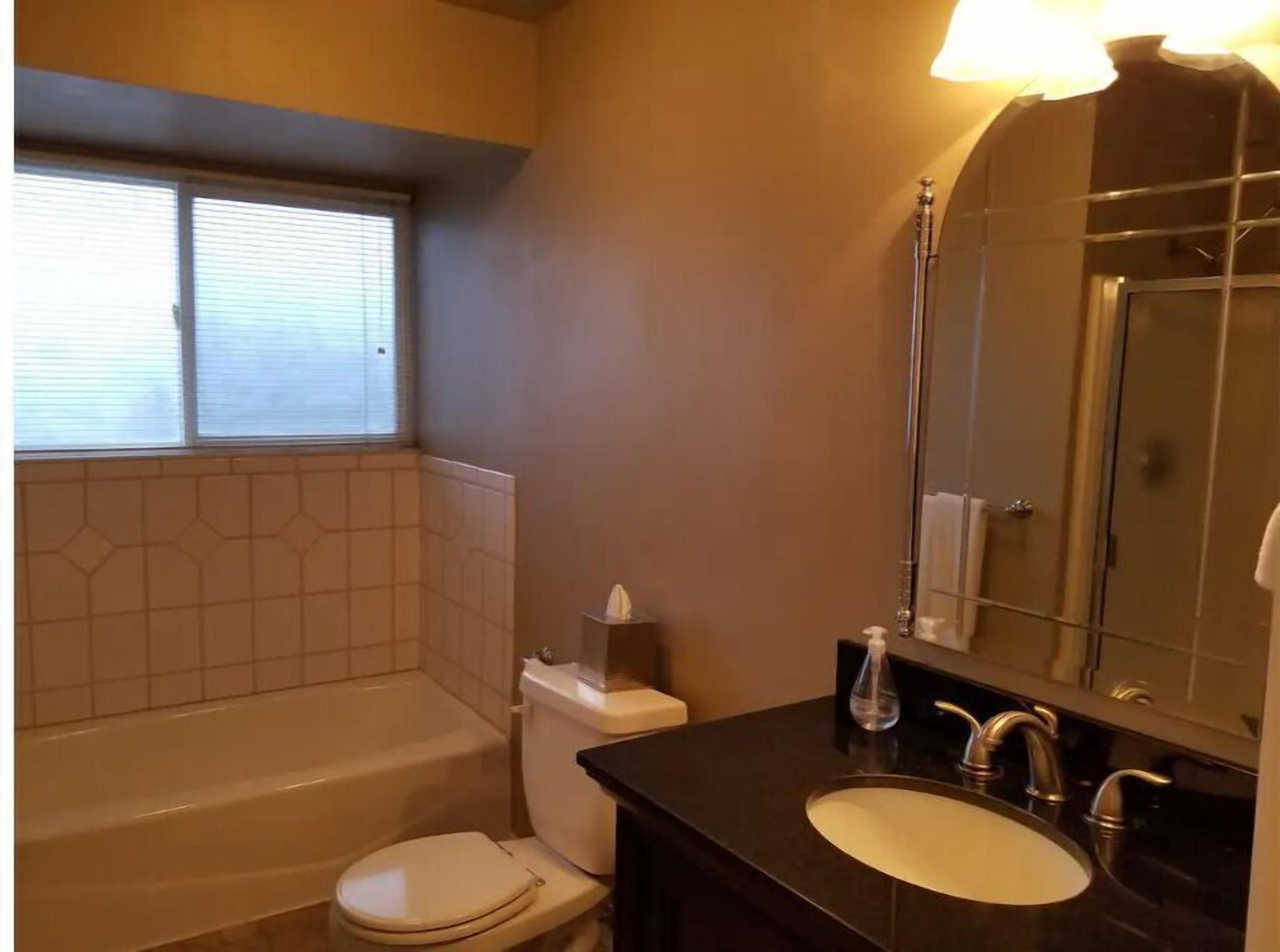 A bathroom with a bathtub, toilet, sink, and a large mirror.