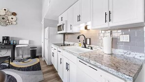 Una cocina moderna con armarios blancos, encimera de granito y microondas integrado.