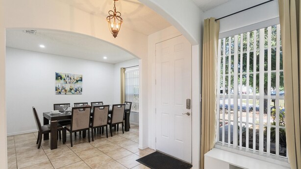 Uma área de refeições com mesa e cadeiras, uma porta branca e uma janela com vista para o exterior.