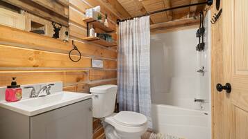 A wooden cabin bathroom with a sink, toilet, and bathtub.