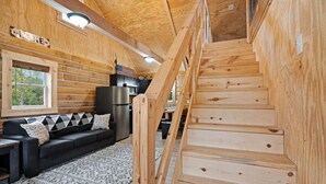 Ein Holzinterieur mit Treppe, einer Couch und einer Küchenzeile.