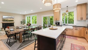A spacious kitchen with wooden cabinets, a large island, and pendant lighting. - Avery House in Newberg: 6 bedrooms, forest views, sleeps 12, ideal for family getaways (Newberg)