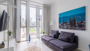 A modern living room with a grey sofa, a round coffee table, and a large window with curtains.