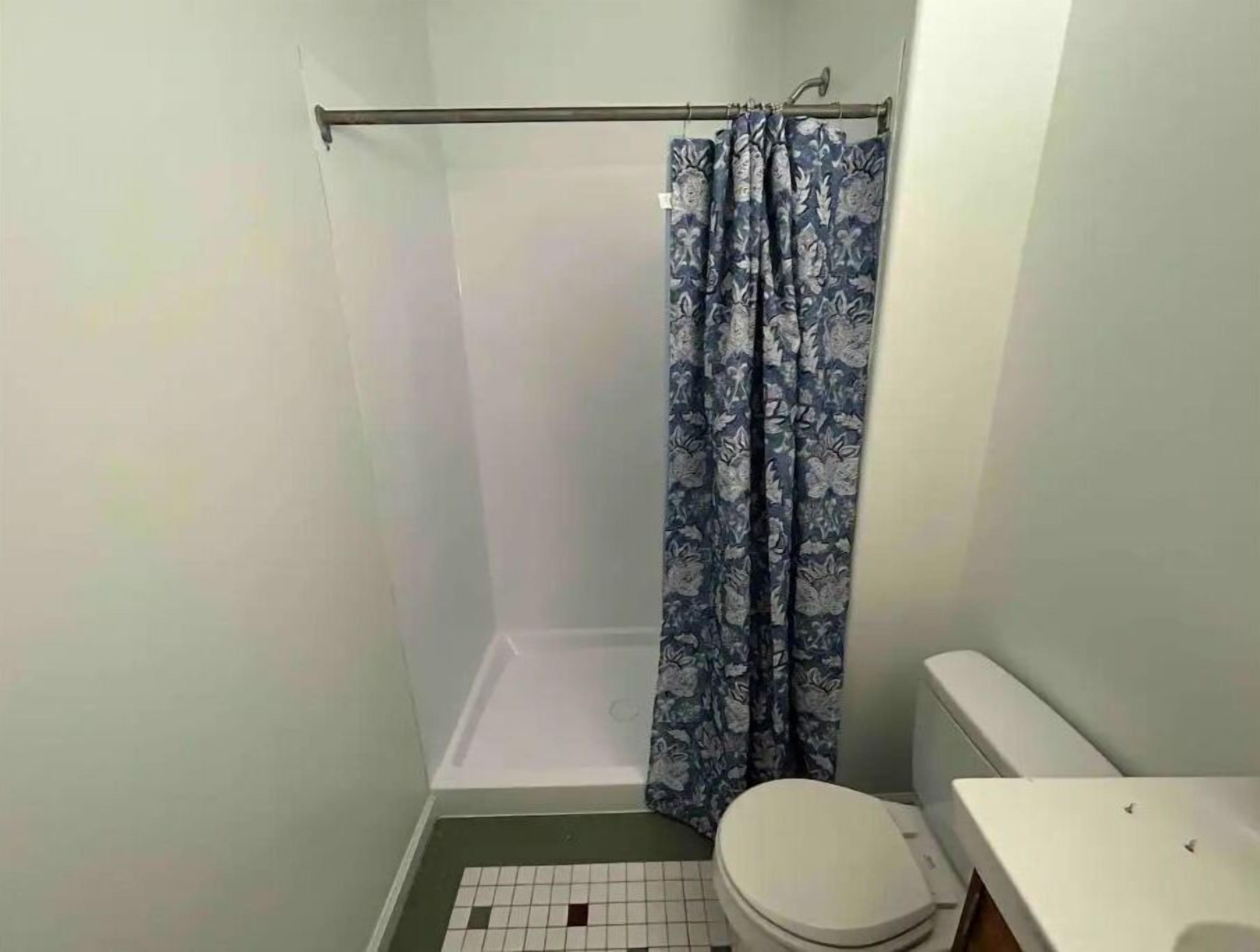 A small bathroom with a shower, toilet, and a tiled floor.