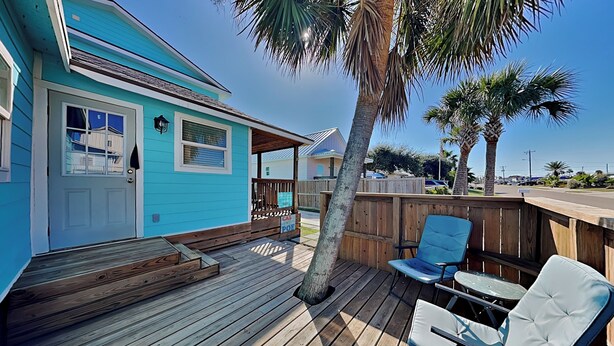 A blue house with a wooden deck, a covered porch, and a sign that reads "CAS POE".