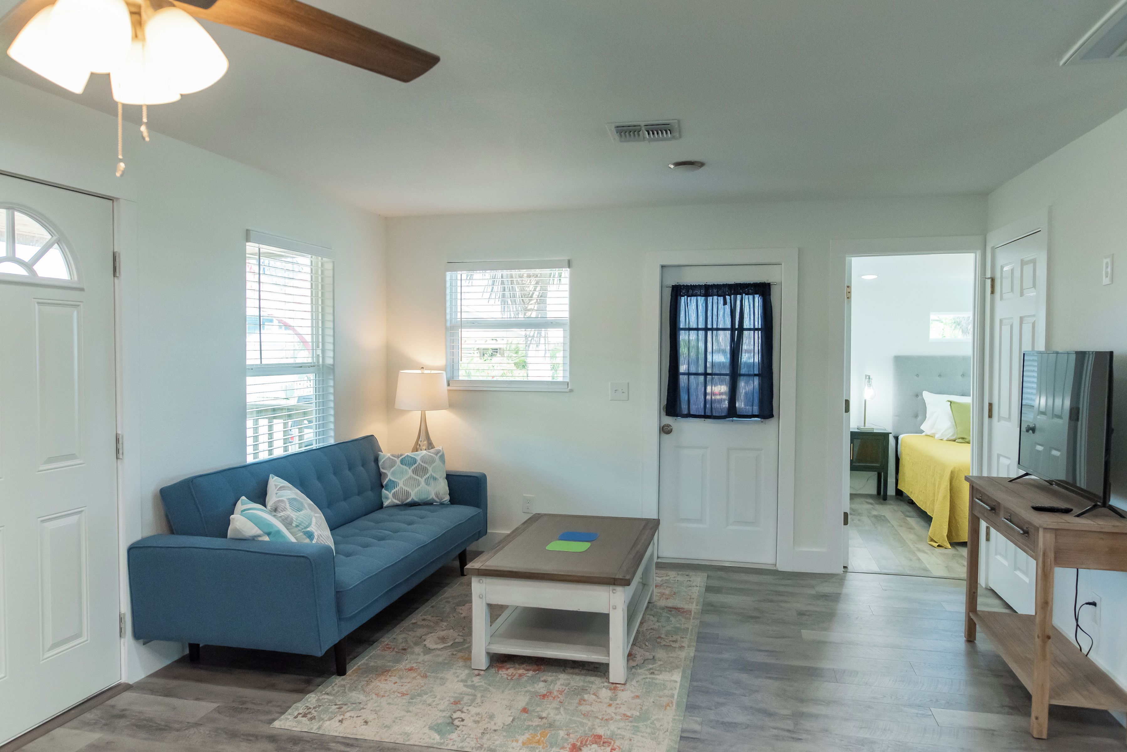 A living room with a blue sofa, a coffee table, a lamp, and a TV stand.