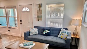 A living room with a grey sofa, a wooden coffee table, and a lamp on a side table. - Casa De Poe by Silver Sands Vacation Rentals (Port Aransas)