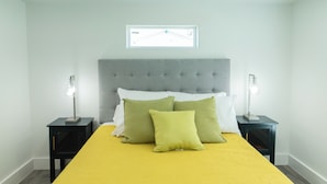 A bedroom with a bed, two nightstands, and a window.