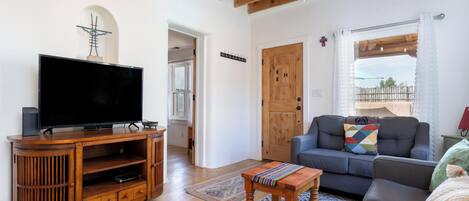 A living room with a wooden entertainment unit, a flat-screen TV, a sofa, and a ceiling fan.