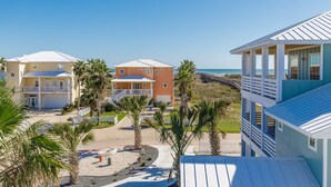 A beachfront hotel with multiple buildings, including a two-story structure with a balcony and a one-story building with a covered patio. - Mermaids Lair by Silver Sands Vacation Rentals (Port Aransas)