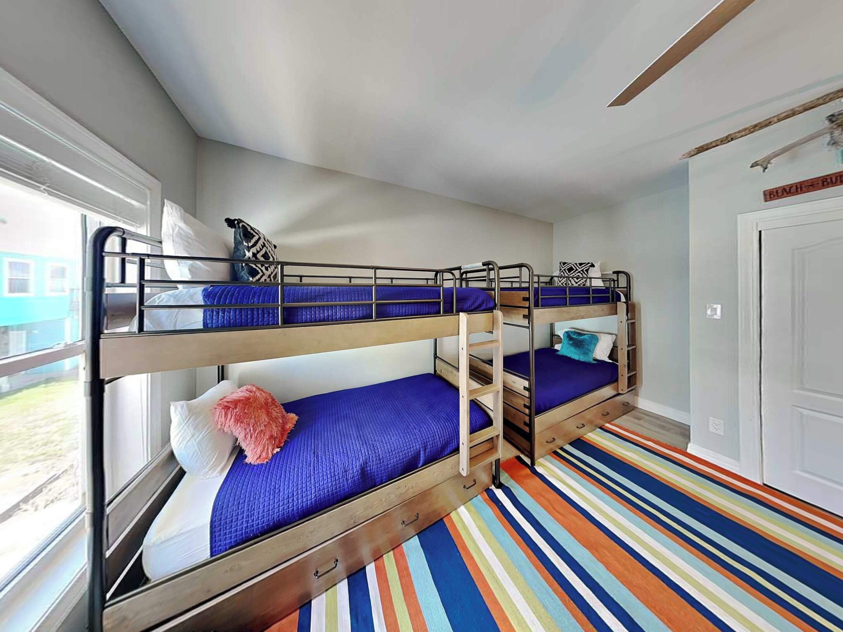 A bunk room with two bunk beds, a striped floor, and a window with a view.