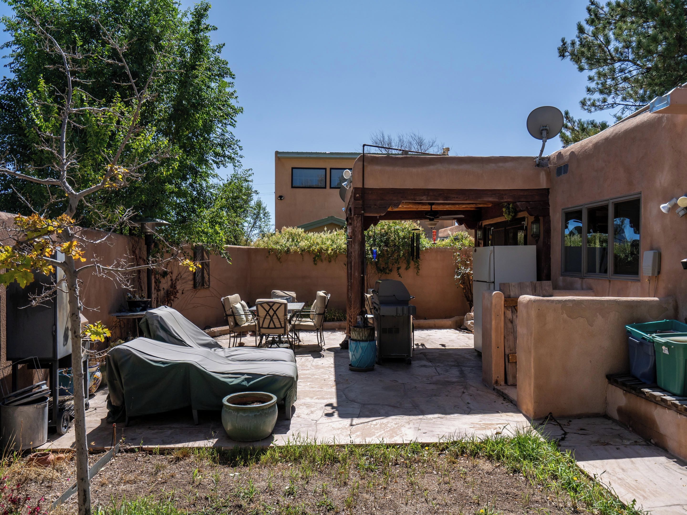 An outdoor patio area with a covered seating area, a barbecue grill, and a satellite dish.