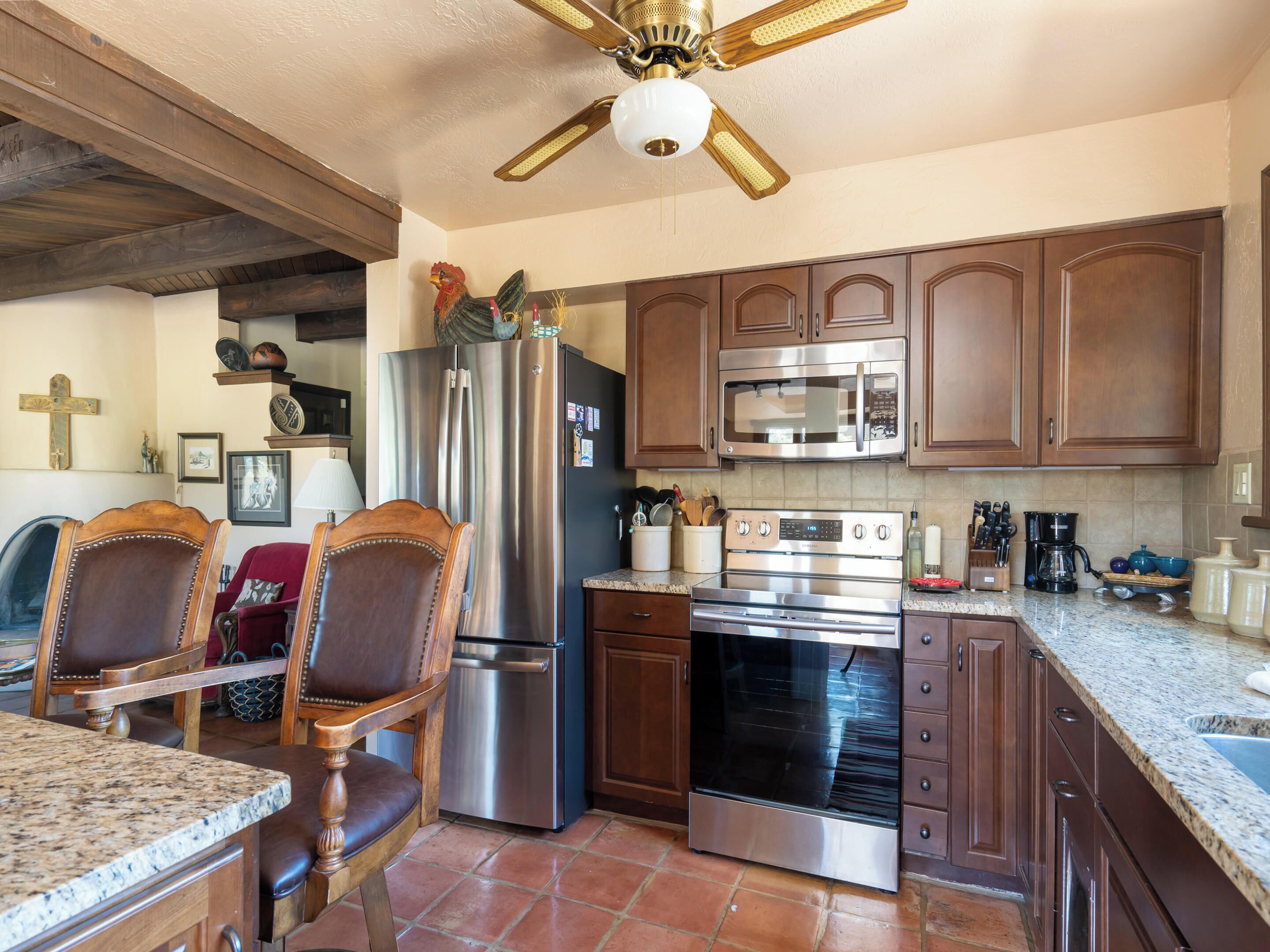 A kitchen with wooden cabinets, stainless steel appliances, and a ceiling fan.