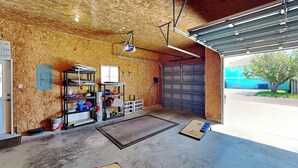 Ett garage med ett betonggolv, träväggar, en metalldörr och en projektor som är monterad i taket.