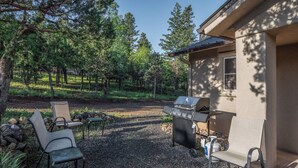 An outdoor patio with two chairs, a grill, and a stone pathway. - Mountain Flo by Ruidoso Vacation Rentals (Alto)